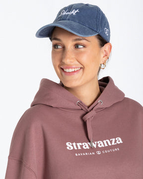 Ein weibliches Model trägt eine Bavarian Cap in der Farbe Vintage Denim und hat als Motiv vorne auf der Cap einen weißen "Obacht" Schriftzug.